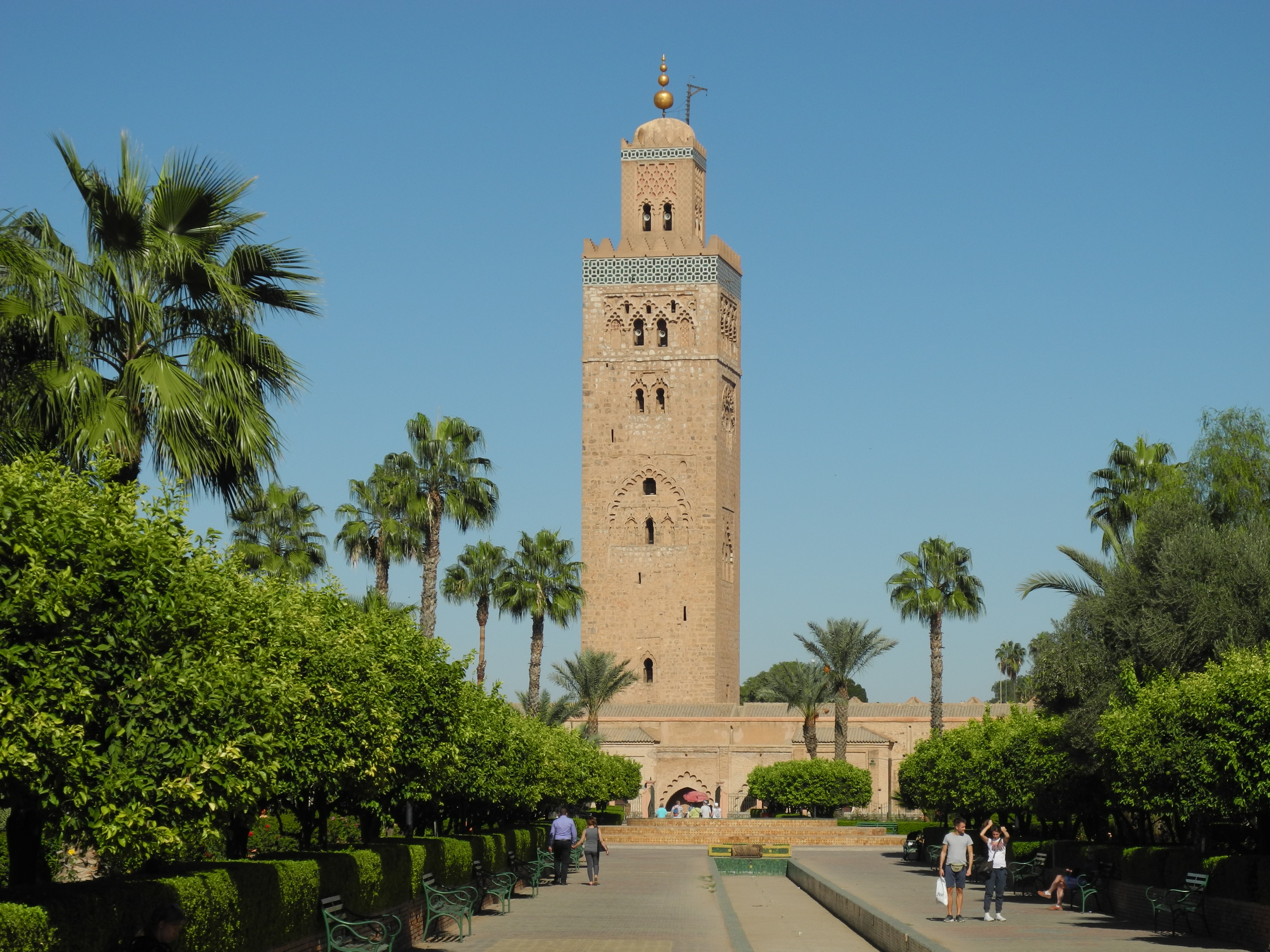 Koutoubia Mosque minaret rising above palm trees and clipped hedges in its garden, Marrakech guided tour
