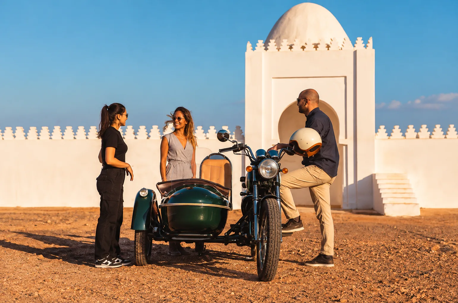 Guide chatting with two women beside a green side-car near a white domed shrine, side-car tour in Marrakech