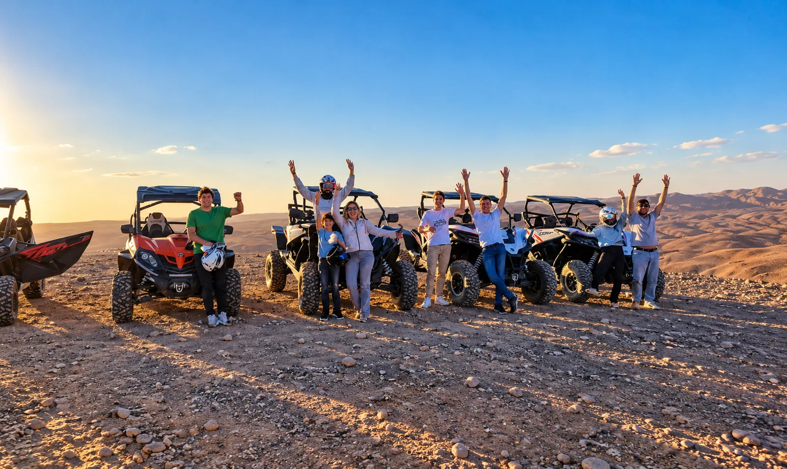 Group celebrating with arms raised in front of their buggies on a ridge, buggy ride in the Agafay desert