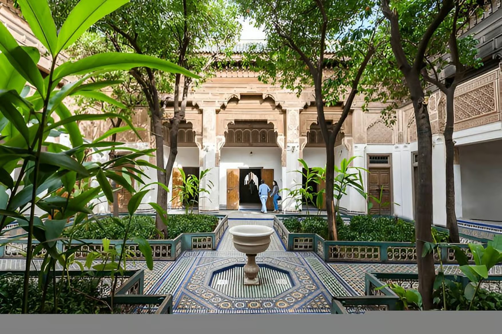 Lush riad garden with a tiled fountain and carved doorways inside a palace, Marrakech guided tour