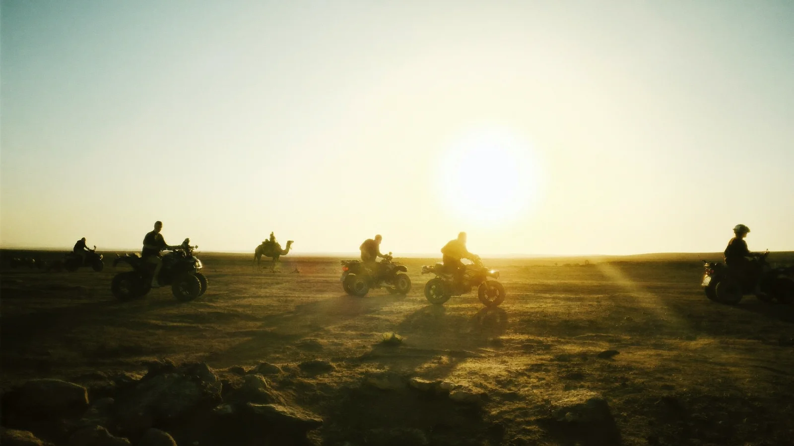 Silhouetten von Quadfahrern auf offenem Gelände, vor ihnen die tiefe Sonne, Quad- und Paintball-Pack in Marrakech
