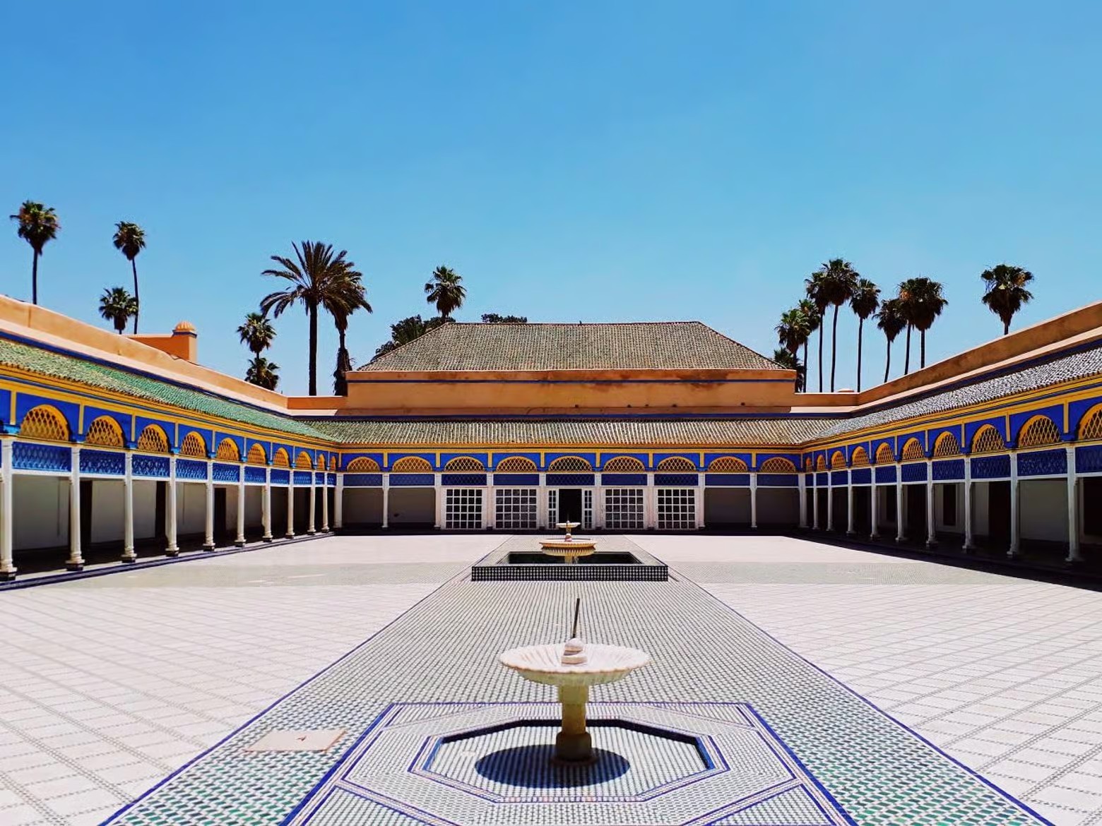 Tiled grand courtyard of Bahia Palace with a central fountain and palm trees, seen on a Marrakech guided tour