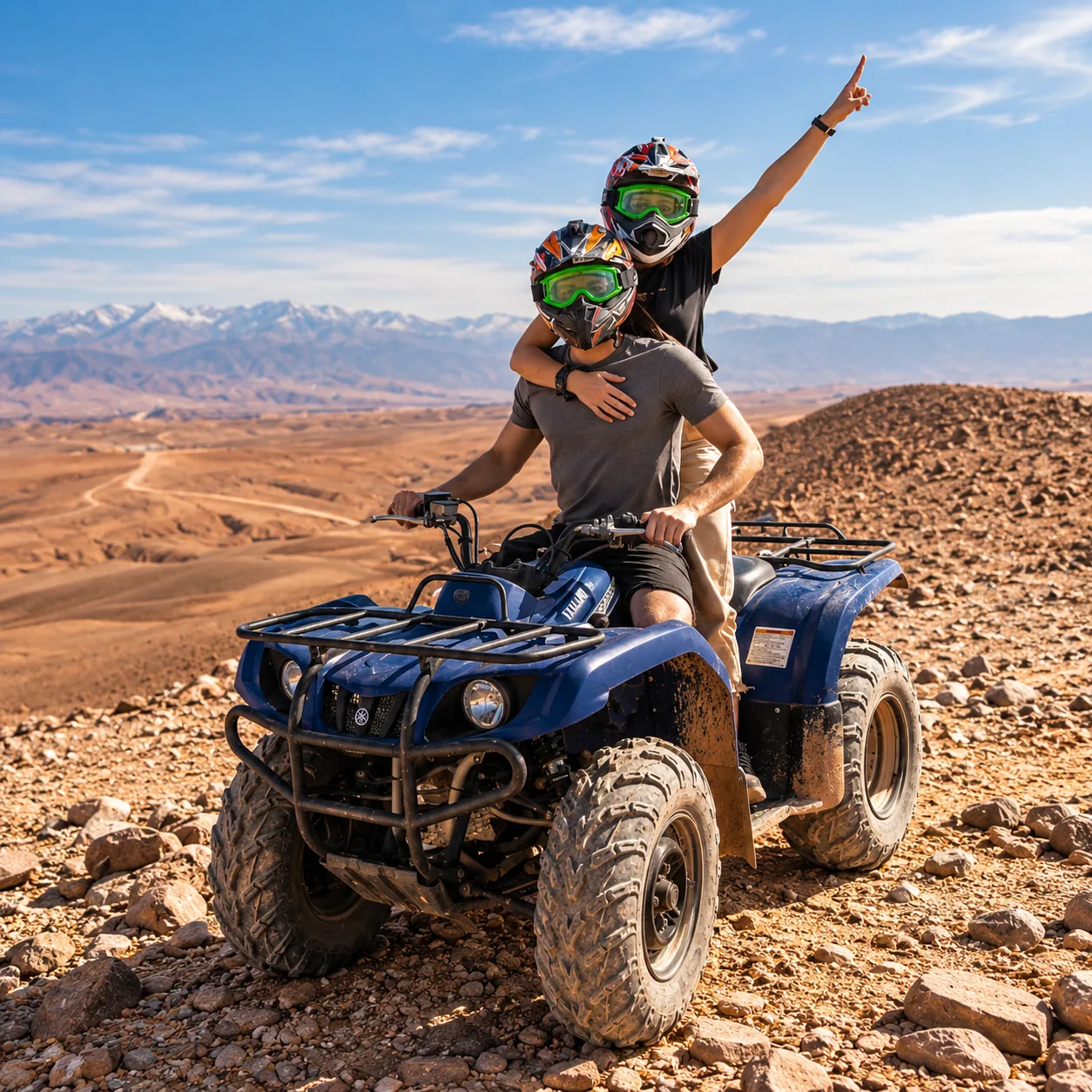 Couple on a blue quad, passenger pointing at the view, quad biking in the Agafay desert with the Atlas behind