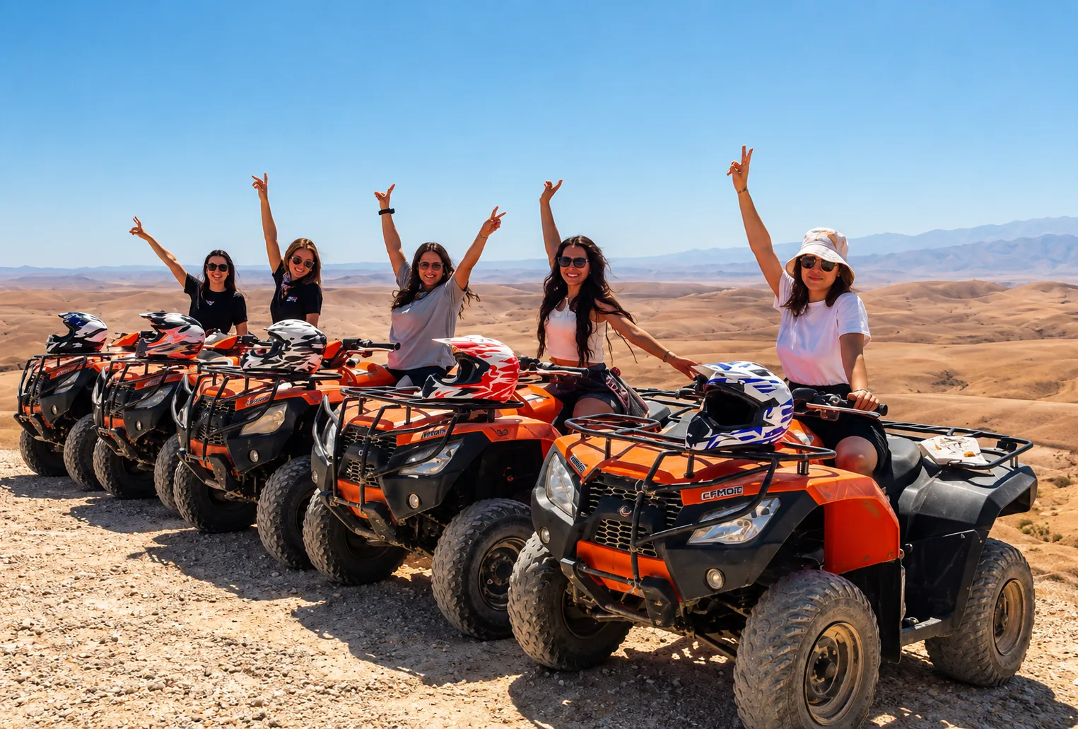 Group of women waving from a row of orange quads before quad biking in the Agafay desert