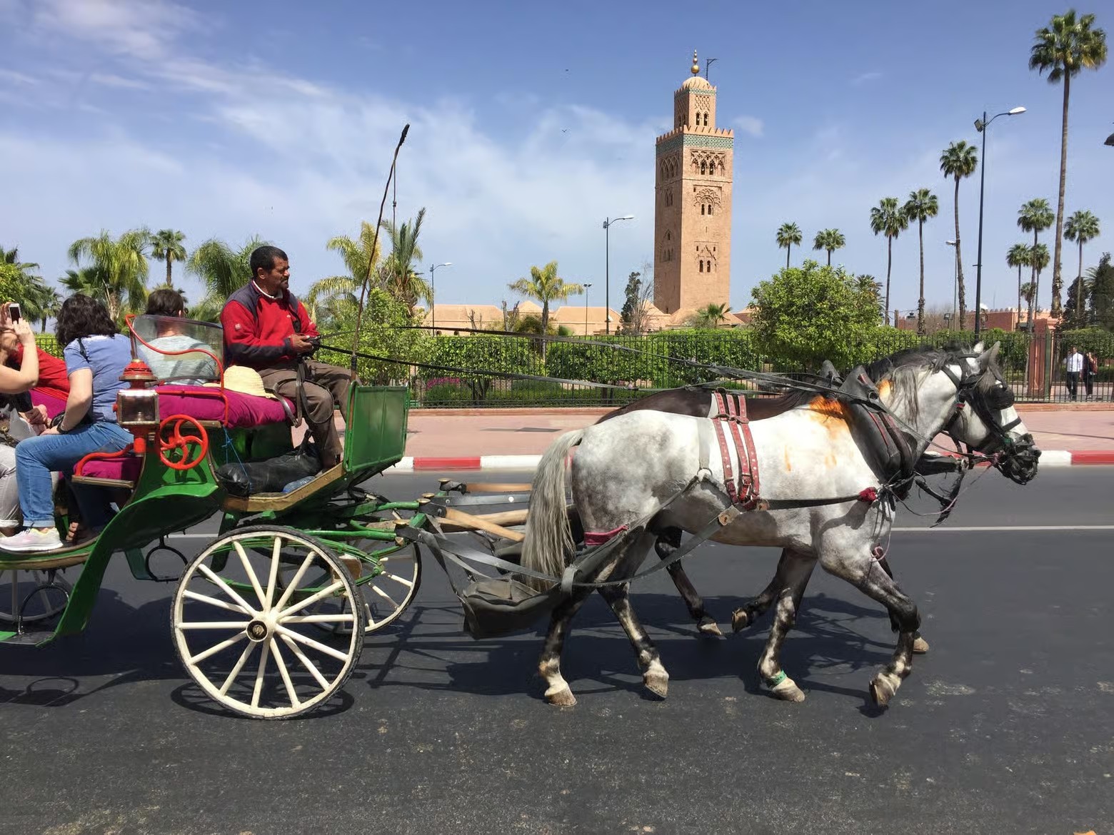 Horse-drawn calèche with passengers on the avenue near the Koutoubia minaret, Marrakech guided tour