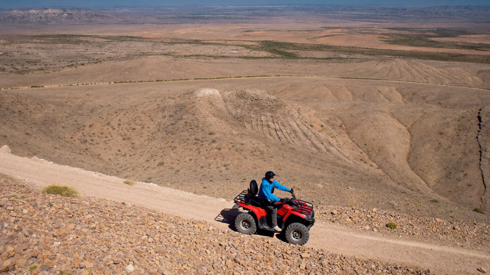 Lone red quad on a track across vast stony hills, quad and camel ride in the Agafay desert near Marrakech