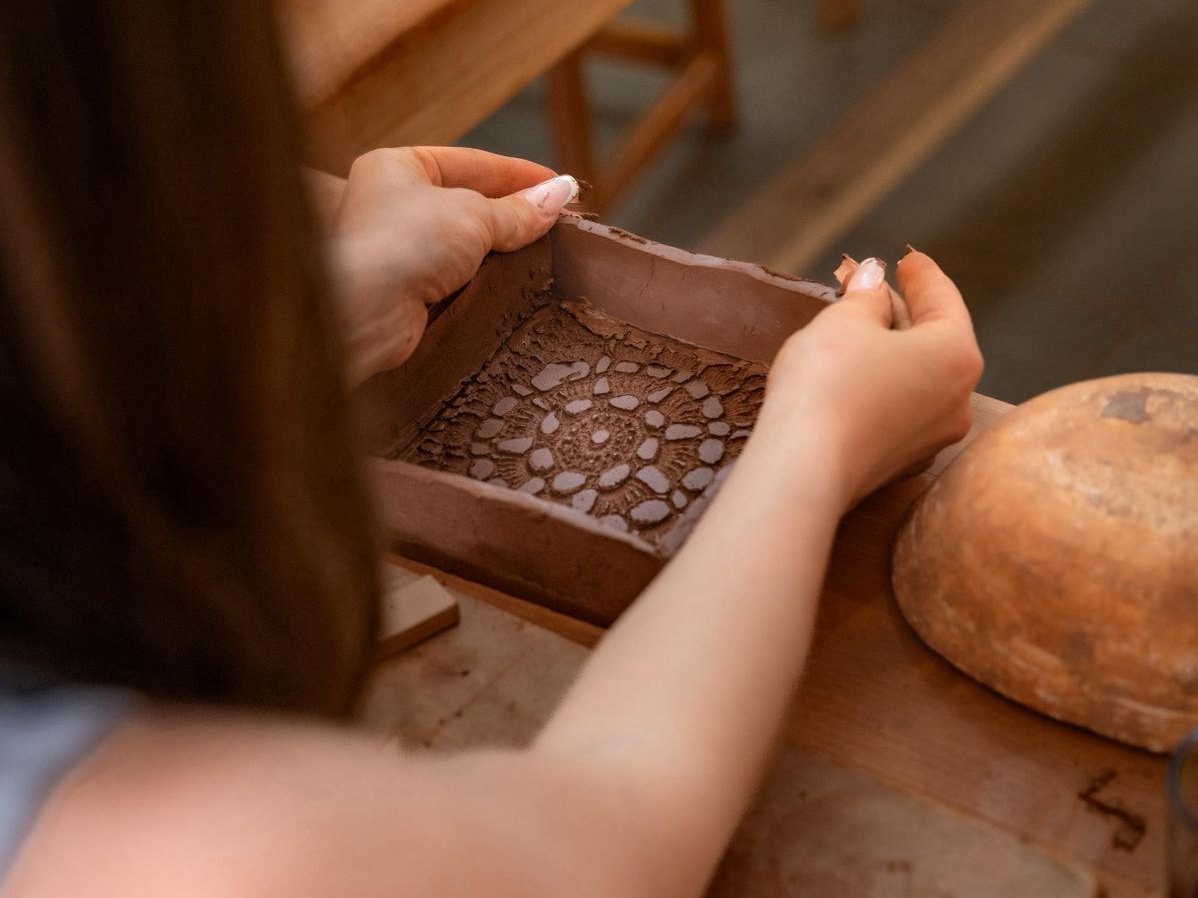 Mani che reggono un vassoietto d'argilla con motivo a pizzo, fatto durante un corso di ceramica a Marrakech