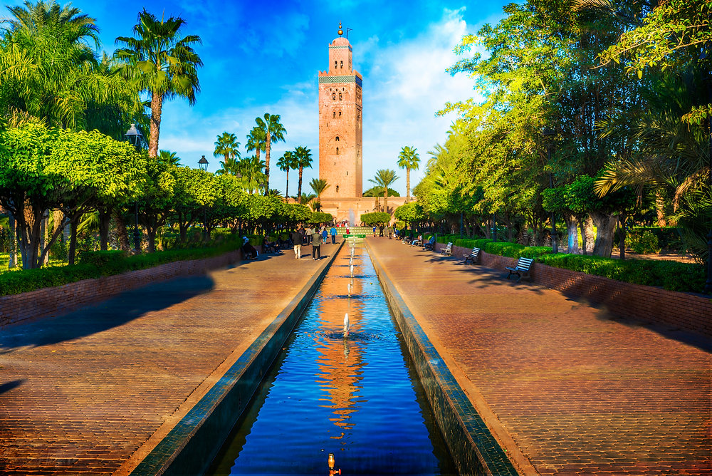 Koutoubia Mosque minaret at the end of a long garden pool lined with trees, Marrakech guided tour