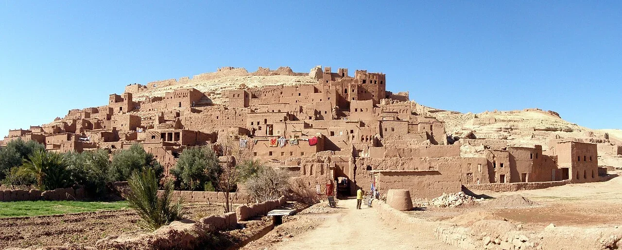 Earthen ksar houses climbing a hillside above green fields, Ouarzazate and Aït Ben Haddou day trip