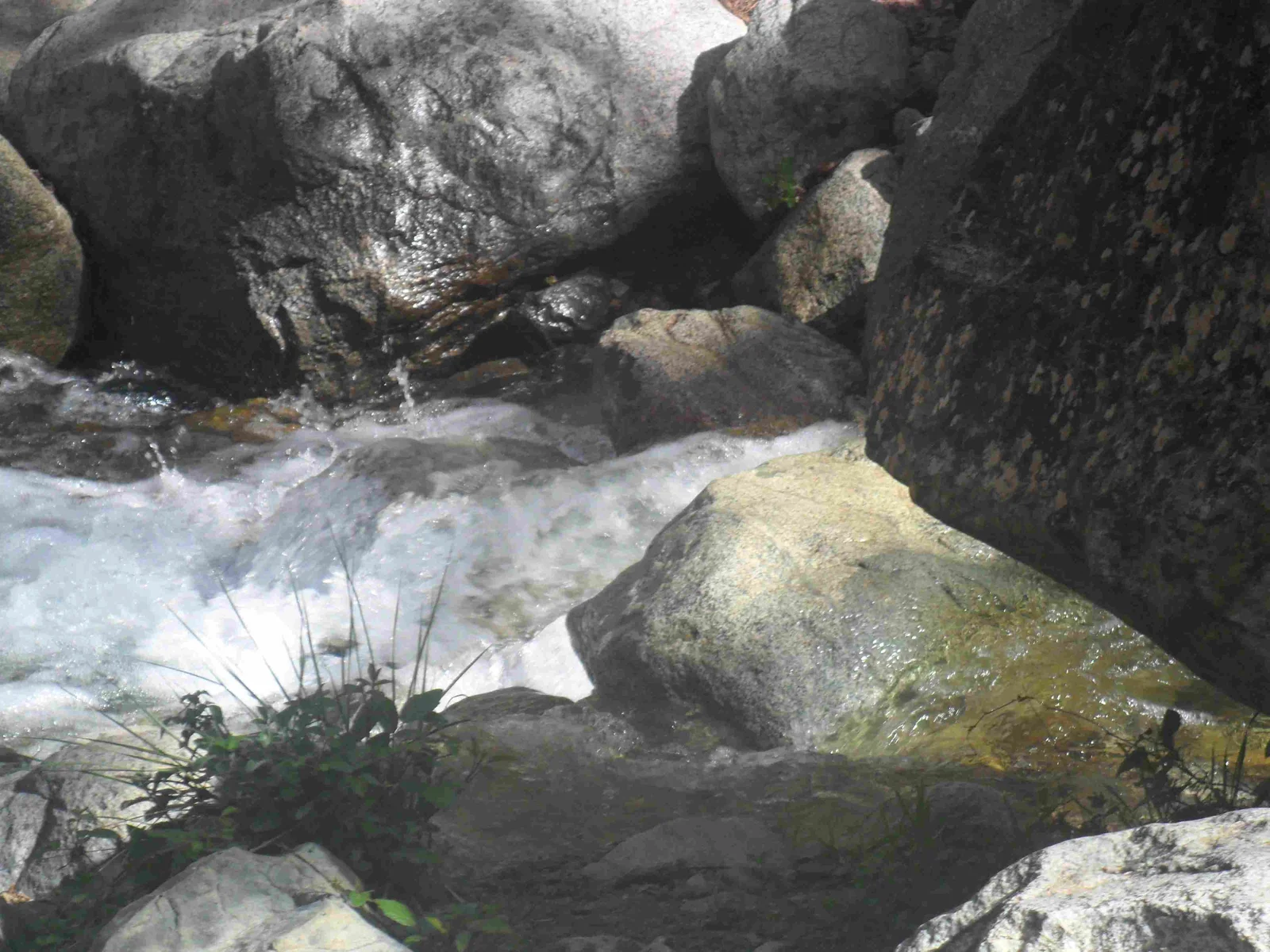 Ruscello limpido tra grandi massi grigi sul sentiero per le cascate, escursione nella valle dell'Ourika