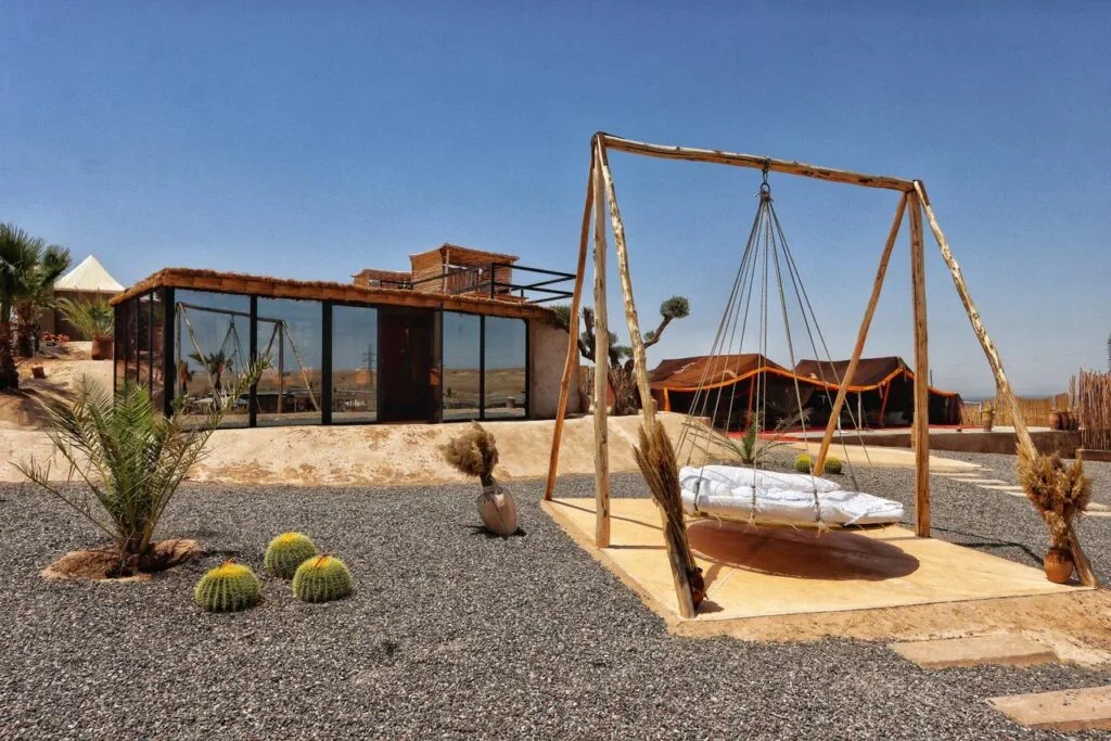 Schaukel-Daybed zwischen Kakteen und Kies vor Lodges mit Glaswänden, La Bohème Agafay Pool- und Mittagessen-Tag