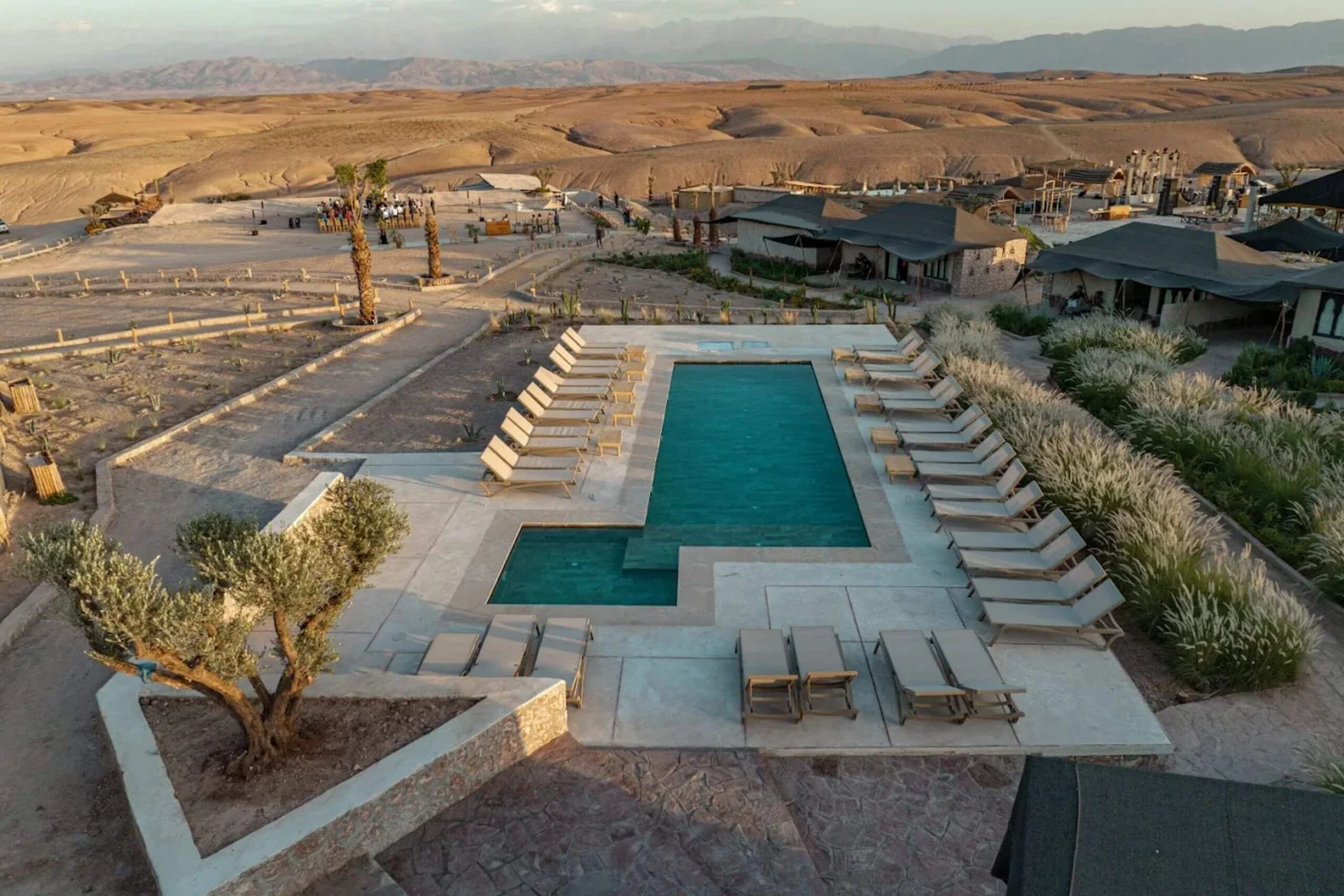 Vista aérea de la piscina con filas de tumbonas y lodges en las colinas, pase de día con piscina en Le Bedouin Agafay