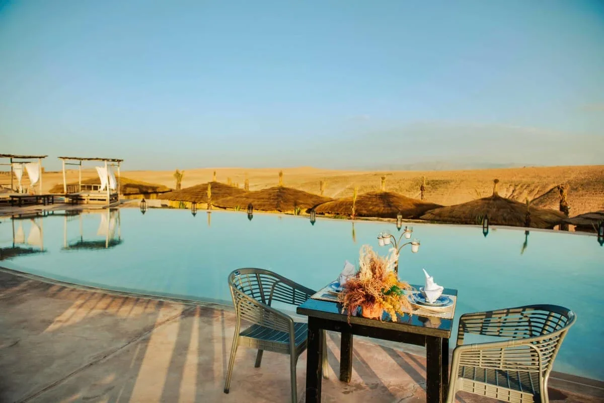Mesa con flores y una tetera al borde de la piscina infinita frente a las colinas, pase de día con piscina en Le Bedouin